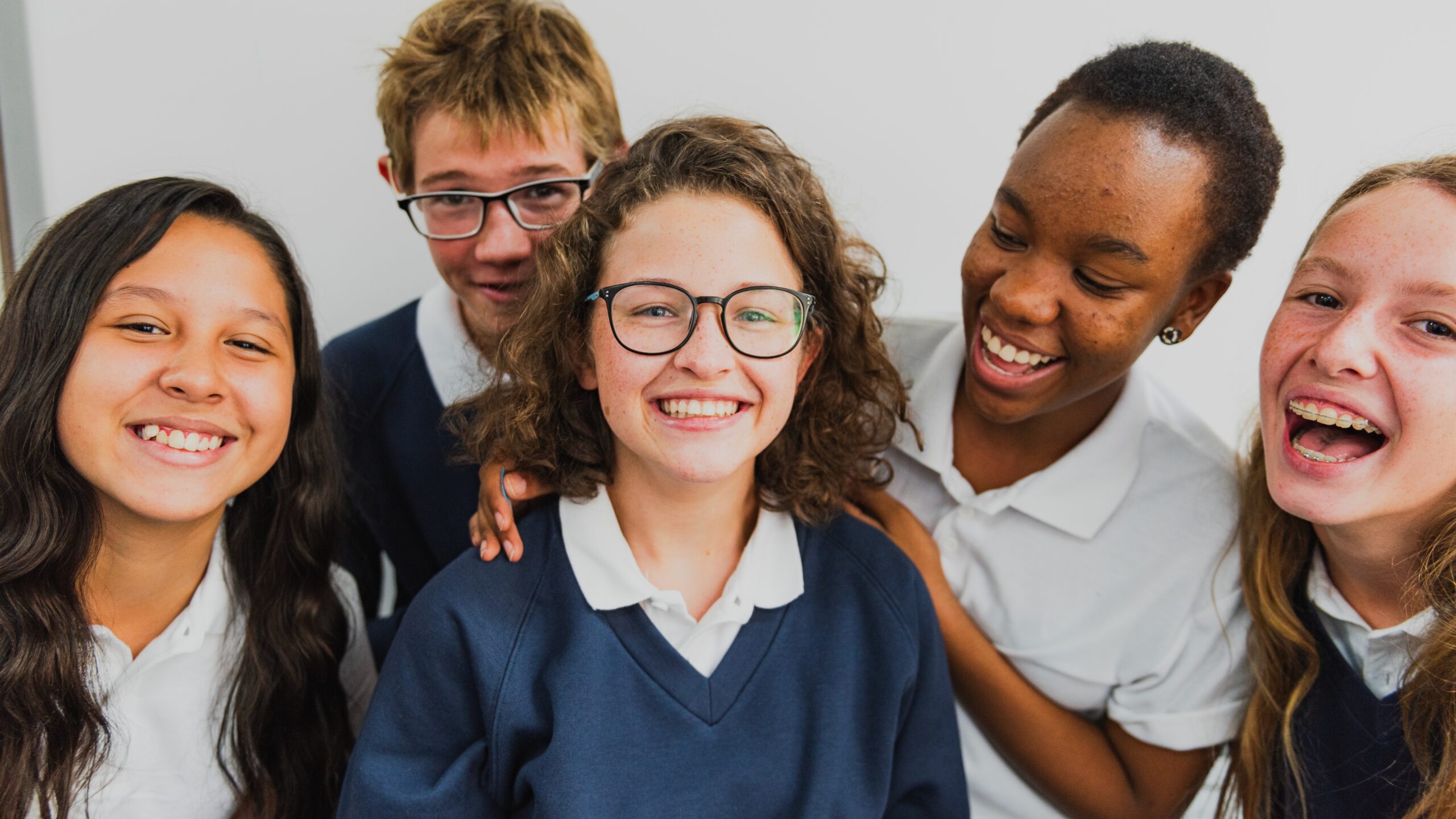 Group of diverse students smiling in school uniforms. Happy students, diverse group, school uniforms. Smiling faces, diverse students, school setting. Diverse international high school students.