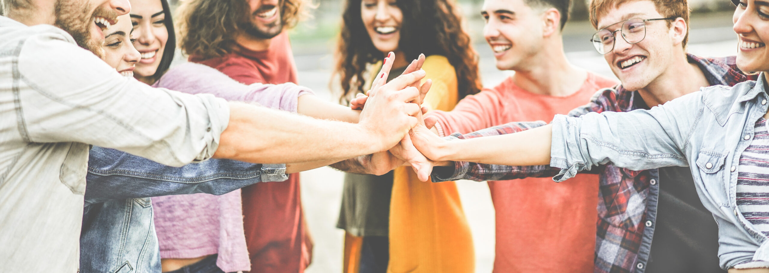 Young happy people stacking hands outdoor - Diverse culture stud