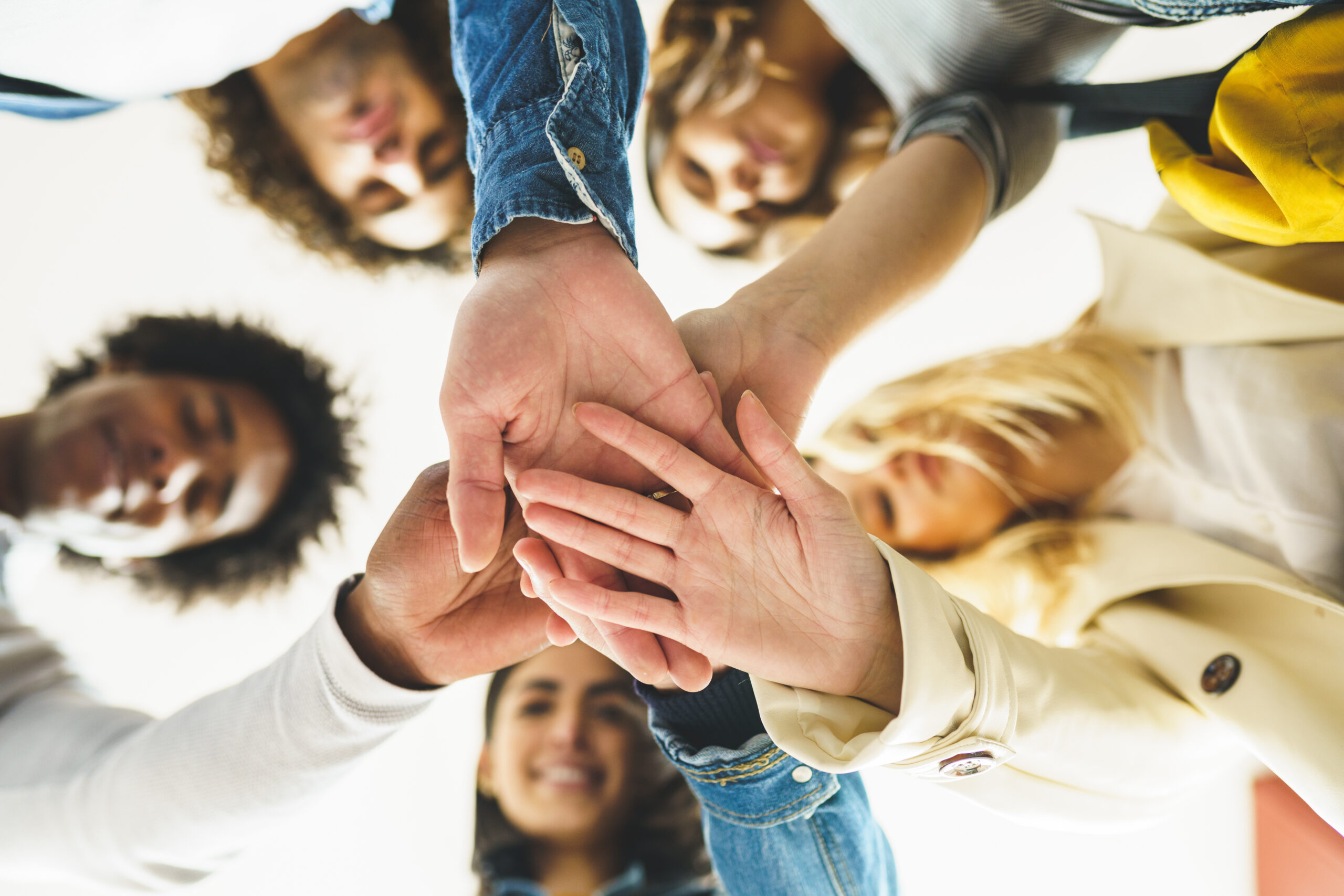 Hands of a multi-ethnic group of friends joined together as a sign of support and teamwork.