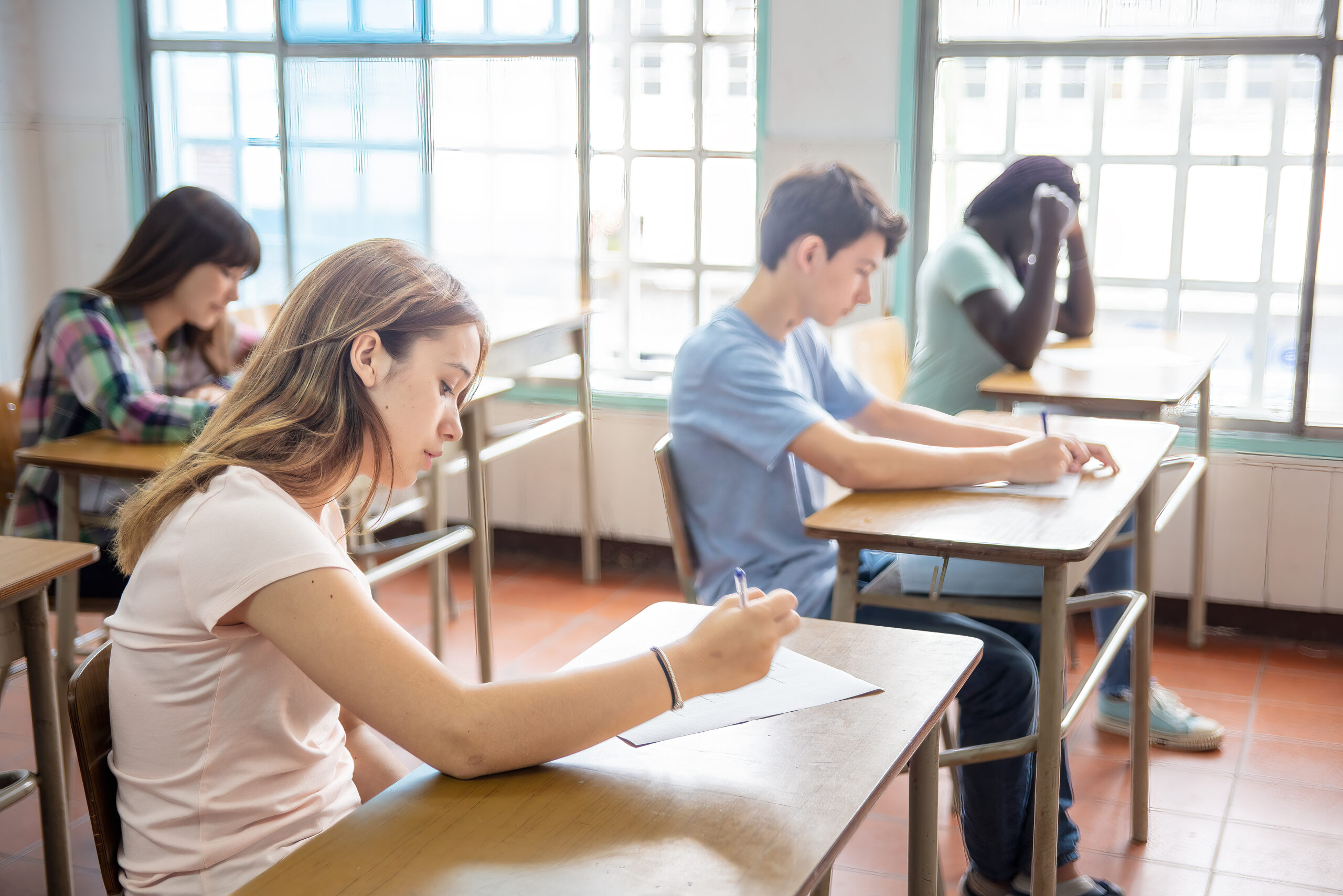 Group of multi ethnic high school students having test at classroom.